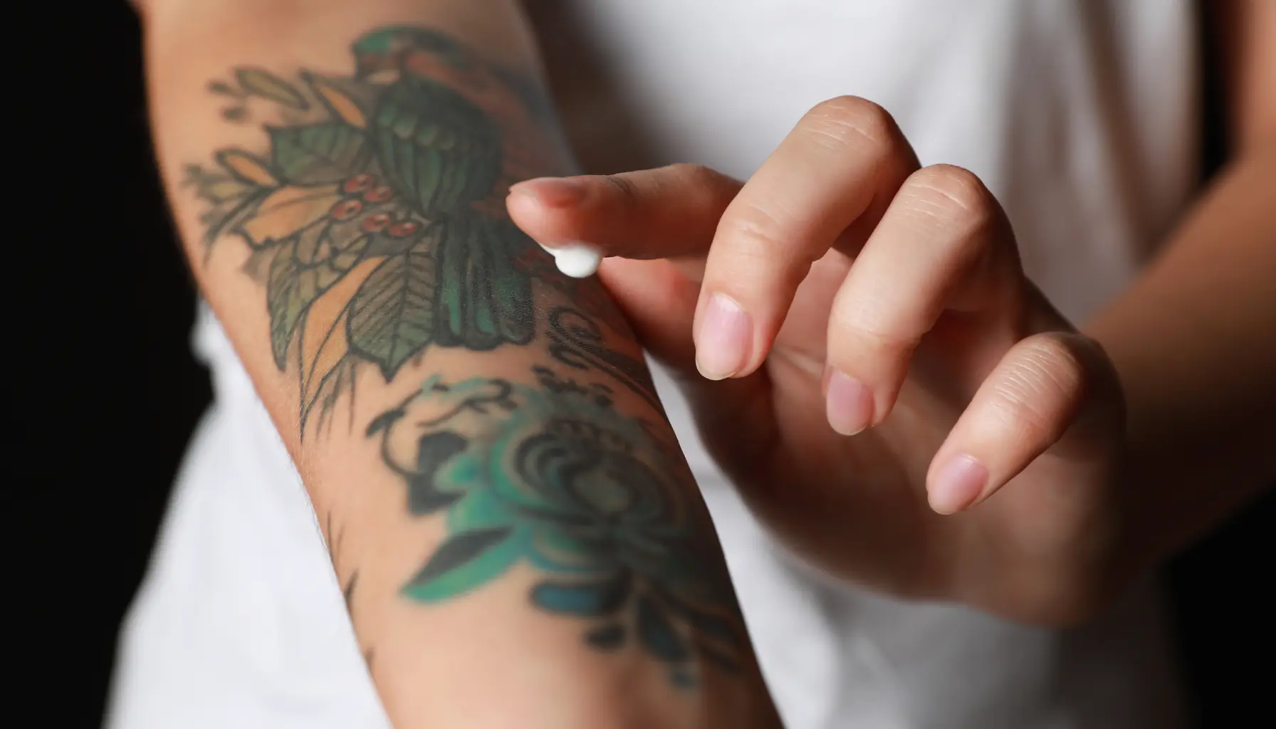 A person applying a thin layer of baby lotion on a new tattoo